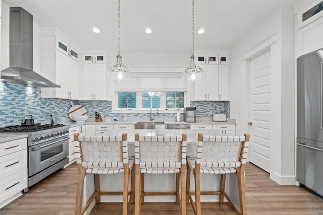 kitchen with white cabinets, wall chimney exhaust hood, a center island, and premium appliances