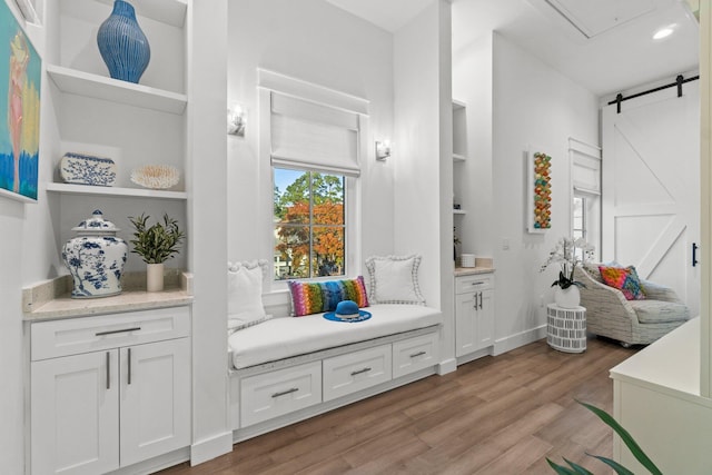 mudroom with a barn door, light hardwood / wood-style floors, and built in features