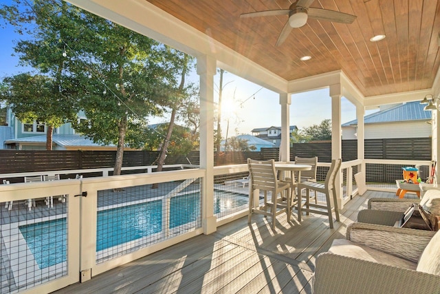 deck featuring ceiling fan and a fenced in pool