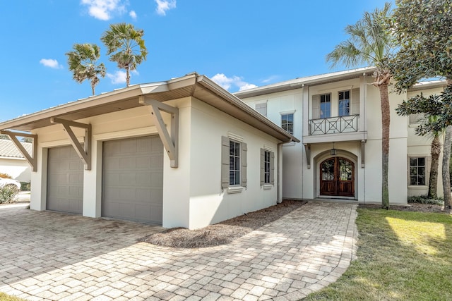 view of front of property with french doors, a balcony, and a garage