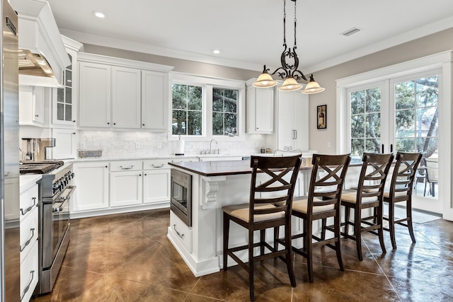 kitchen featuring a breakfast bar area, white cabinetry, a center island, appliances with stainless steel finishes, and decorative backsplash