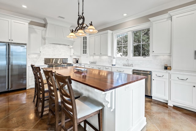 kitchen with a kitchen island, white cabinetry, appliances with stainless steel finishes, and wood counters