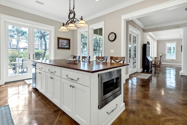 kitchen featuring pendant lighting, stainless steel microwave, white cabinets, and french doors