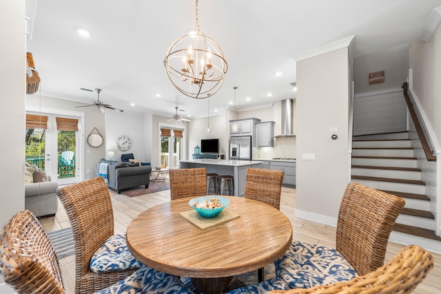 dining space with crown molding, ceiling fan with notable chandelier, and light wood-type flooring