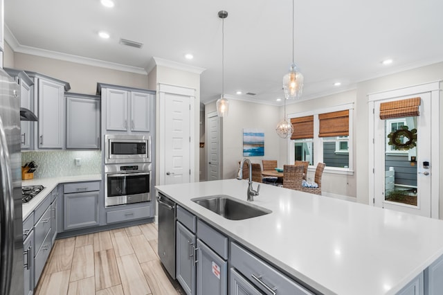 kitchen with decorative light fixtures, sink, gray cabinetry, a kitchen island with sink, and stainless steel appliances