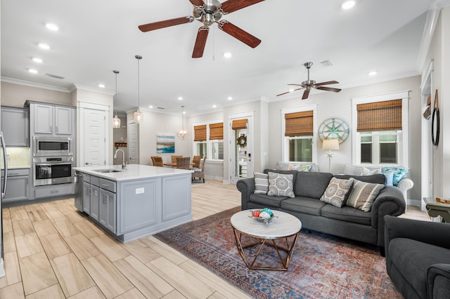 living room featuring ornamental molding, sink, and light hardwood / wood-style flooring