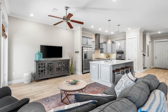 living room with sink, ornamental molding, light hardwood / wood-style floors, and ceiling fan