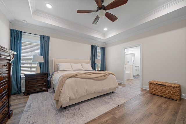 bedroom featuring a tray ceiling, baseboards, wood finished floors, and ornamental molding