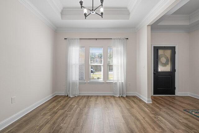 entryway with baseboards, a chandelier, a tray ceiling, ornamental molding, and wood finished floors