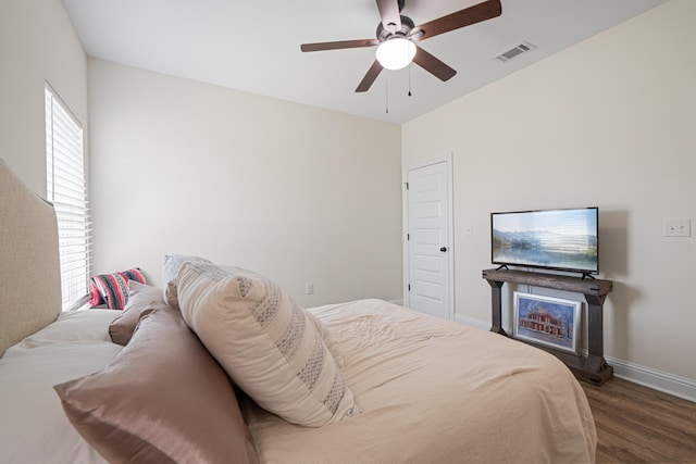 bedroom featuring a ceiling fan, wood finished floors, visible vents, and baseboards