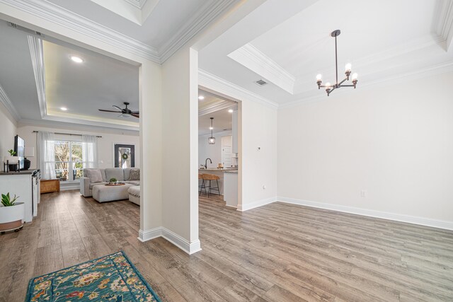 interior space with crown molding, a raised ceiling, baseboards, and wood finished floors