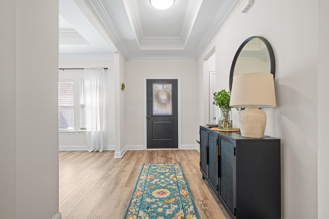 foyer with a raised ceiling, baseboards, light wood-type flooring, and ornamental molding