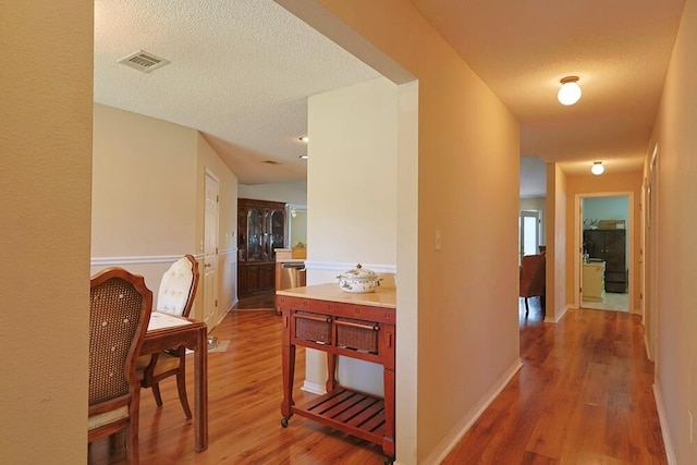 5205 Whitehurst Ln, Crestview, FL 32536 - hall featuring light wood-style flooring, a textured ceiling, and baseboards