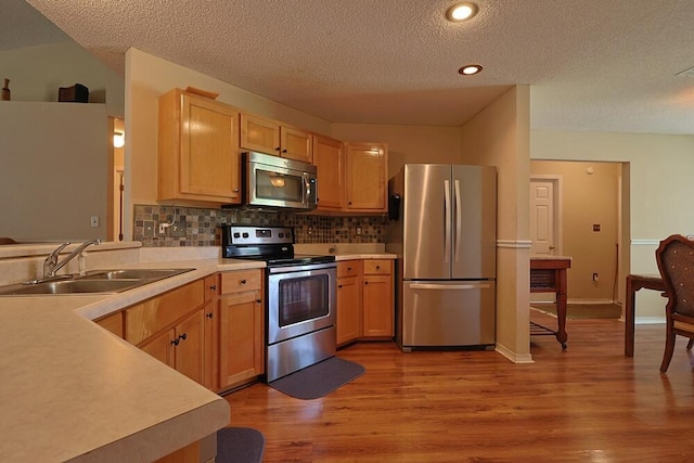 5205 Whitehurst Ln, Crestview, FL 32536 - kitchen featuring appliances with stainless steel finishes, a sink, a textured ceiling, light wood-style flooring, and decorative backsplash
