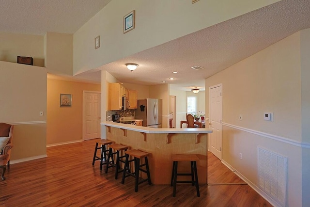 5205 Whitehurst Ln, Crestview, FL 32536 - kitchen featuring stainless steel appliances, a breakfast bar, dark wood finished floors, a peninsula, and a textured ceiling