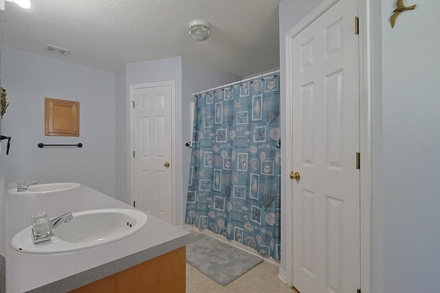 5205 Whitehurst Ln, Crestview, FL 32536 - bathroom featuring double vanity, a textured ceiling, tile patterned flooring, and a shower with curtain