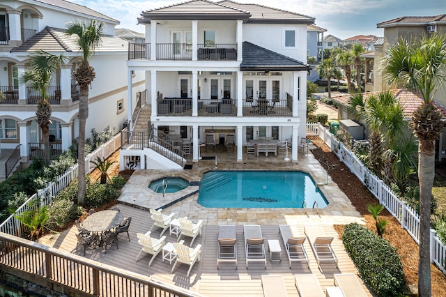 rear view of property with a pool with hot tub, a patio, and a balcony