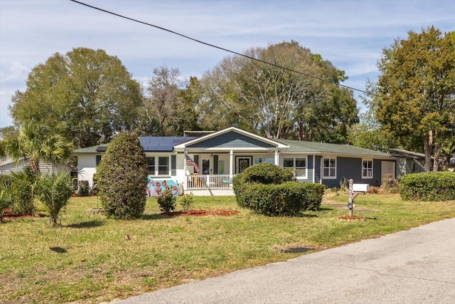 single story home featuring covered porch, solar panels, and a front lawn