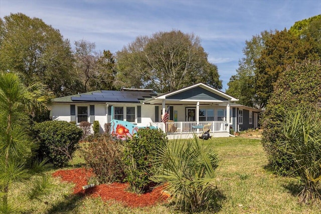 view of front of property with roof mounted solar panels, a front lawn, and a porch