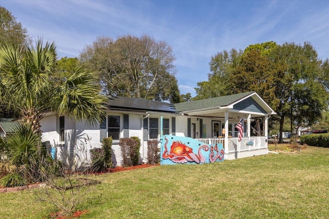 exterior space with covered porch, roof mounted solar panels, brick siding, and a front yard