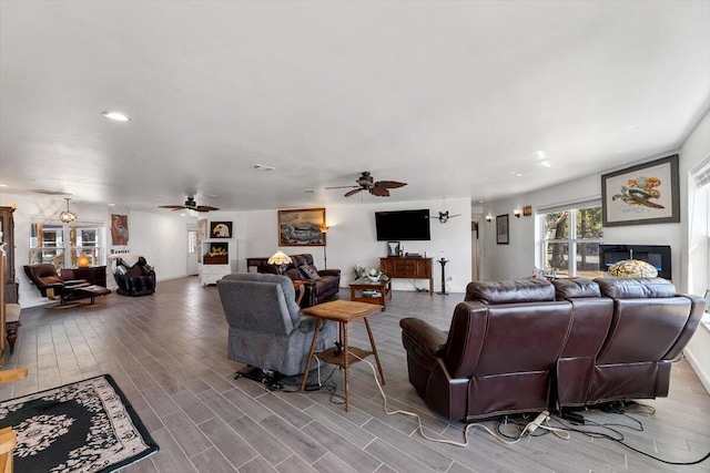 living area with a fireplace, wood finished floors, and a ceiling fan