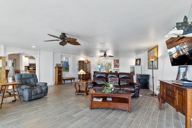 living room featuring arched walkways, visible vents, a ceiling fan, and wood tiled floor