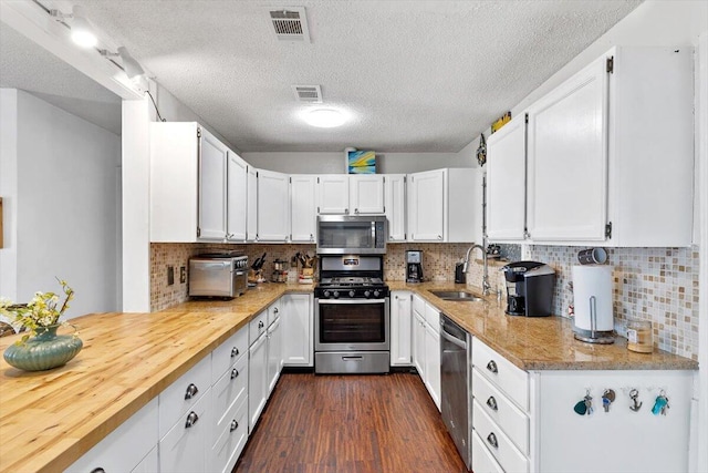 kitchen with appliances with stainless steel finishes, white cabinets, visible vents, and a sink