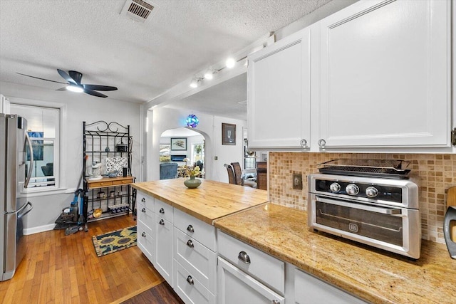 kitchen featuring a toaster, tasteful backsplash, visible vents, wood-type flooring, and freestanding refrigerator