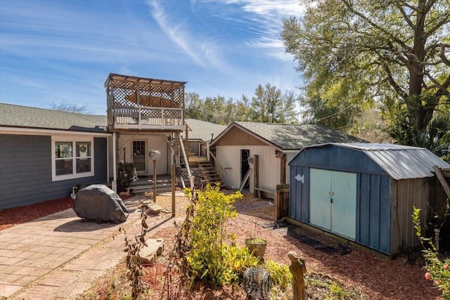 rear view of property featuring an outbuilding, a patio, stairway, a storage shed, and a wooden deck