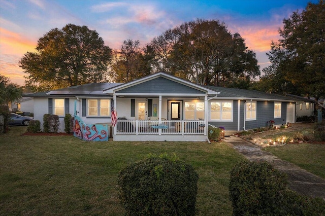 single story home with solar panels, a porch, and a front lawn