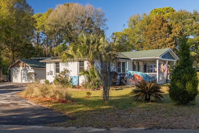 view of front of house featuring covered porch, a front lawn, and a garage