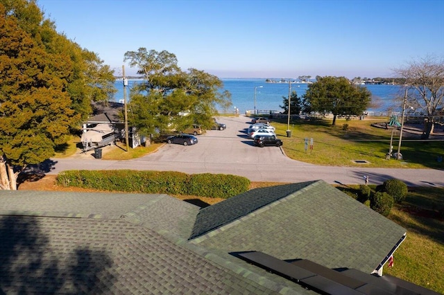 exterior space featuring uncovered parking, a water view, and a yard