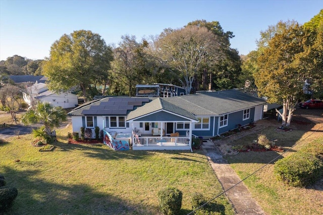 rear view of house with a yard and solar panels