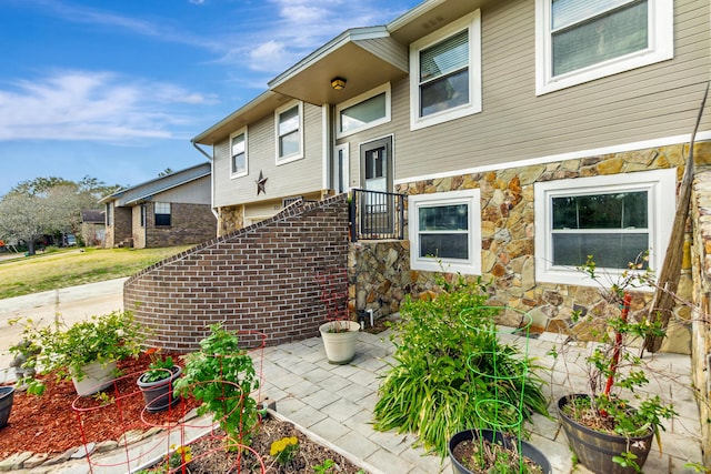 doorway to property featuring stone siding and a patio area