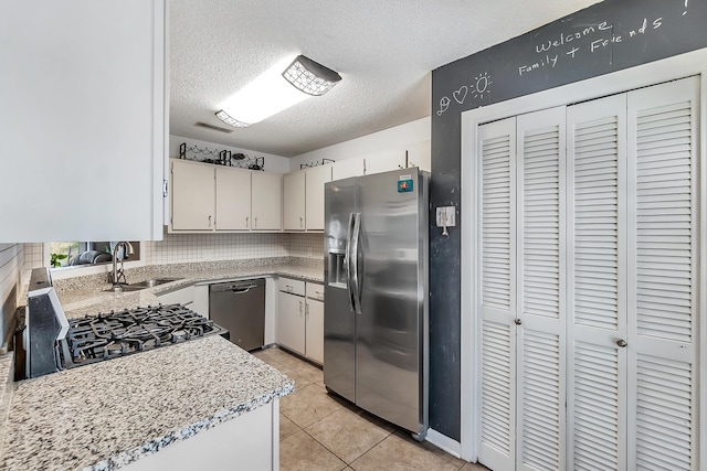 kitchen with light tile patterned floors, visible vents, stainless steel appliances, light countertops, and a sink