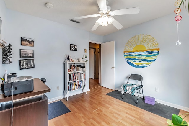 office space with a ceiling fan, visible vents, baseboards, and wood finished floors