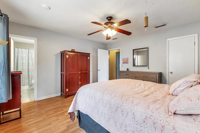 bedroom with light wood finished floors, baseboards, visible vents, ceiling fan, and a textured ceiling