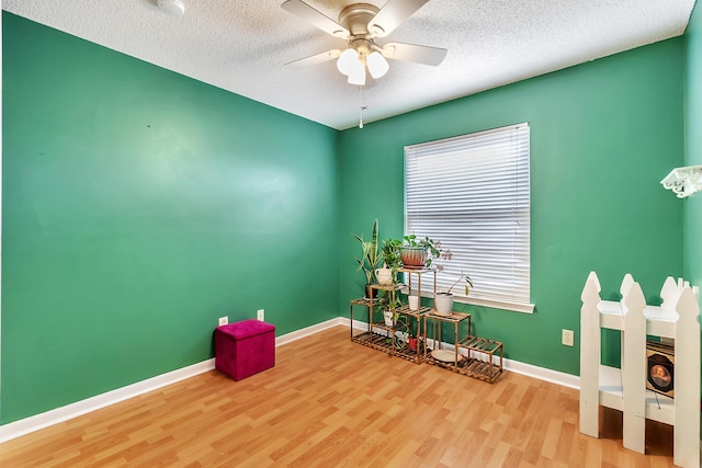 miscellaneous room featuring a textured ceiling, wood finished floors, a ceiling fan, and baseboards