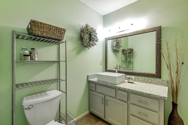 bathroom featuring baseboards, toilet, tile patterned floors, a textured ceiling, and vanity