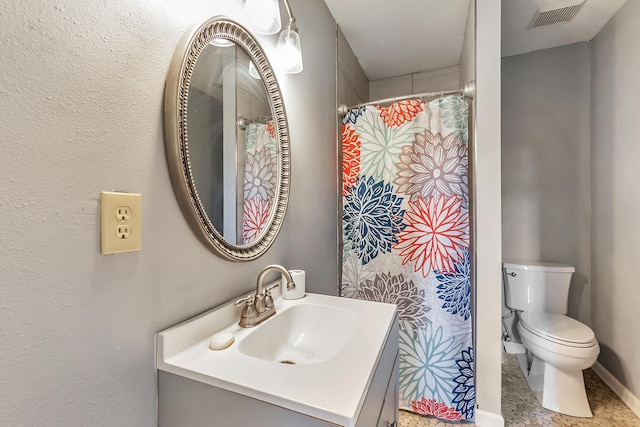 bathroom featuring toilet, vanity, and visible vents