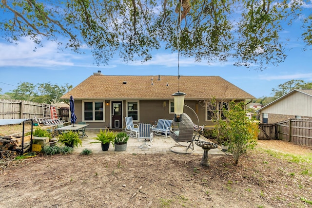 back of property featuring a fenced backyard, a shingled roof, and a patio