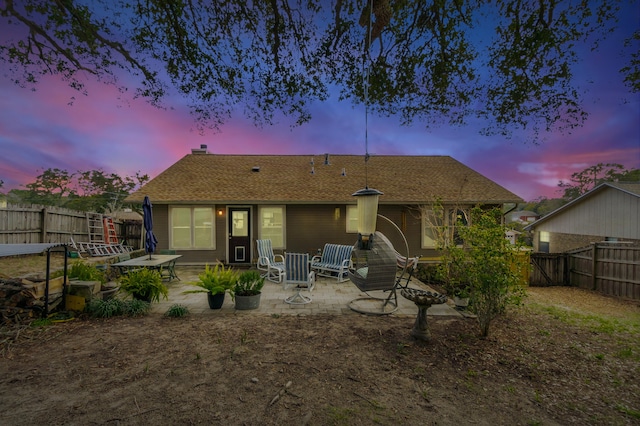 back of property featuring a fenced backyard, roof with shingles, and a patio