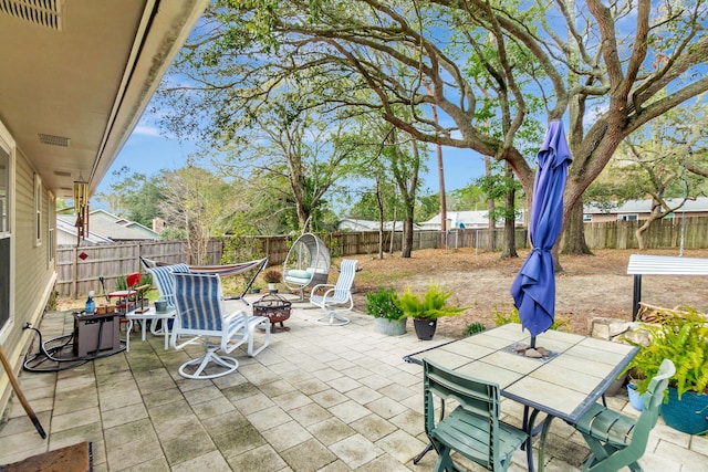 view of patio featuring an outdoor fire pit, visible vents, a fenced backyard, and outdoor dining space