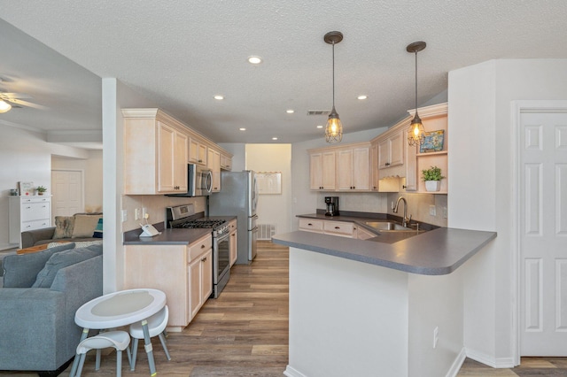 kitchen featuring sink, wood-type flooring, hanging light fixtures, appliances with stainless steel finishes, and kitchen peninsula