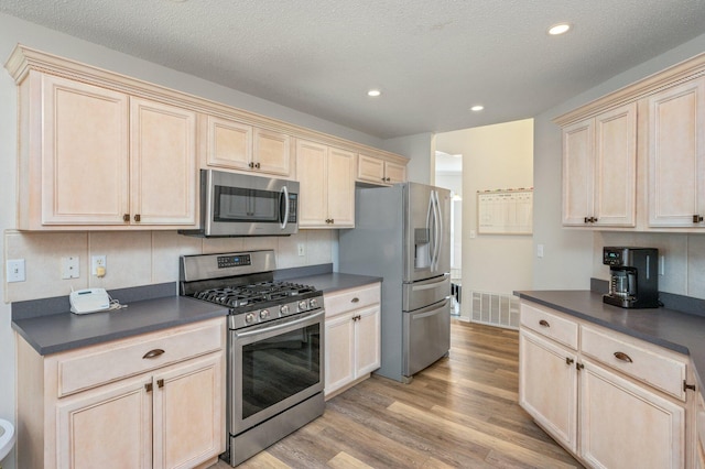 kitchen with appliances with stainless steel finishes, a textured ceiling, and light wood-type flooring