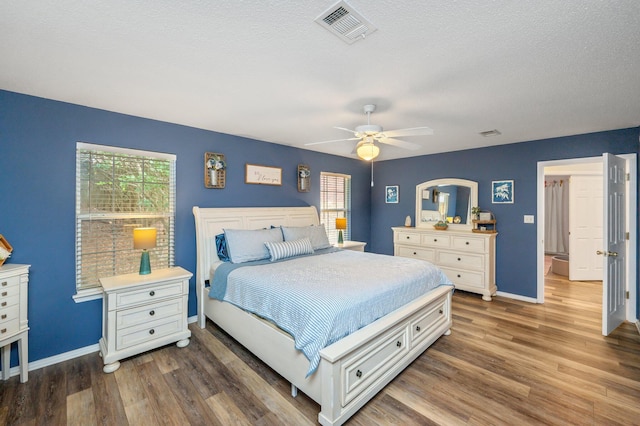 bedroom featuring ceiling fan, dark hardwood / wood-style flooring, and a textured ceiling