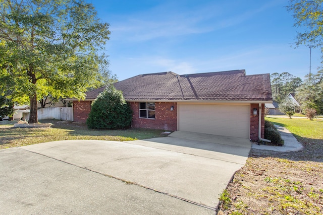 ranch-style house featuring an attached garage, a front lawn, concrete driveway, and brick siding