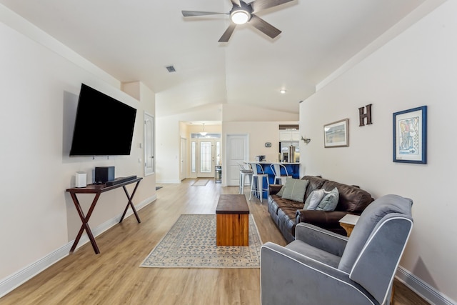 living room featuring light wood-style flooring, visible vents, vaulted ceiling, and baseboards