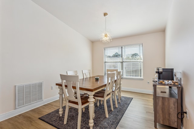 dining room featuring a chandelier, light wood-style flooring, visible vents, and baseboards