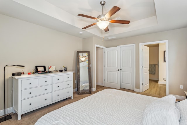 bedroom featuring visible vents, baseboards, a raised ceiling, ceiling fan, and ensuite bathroom